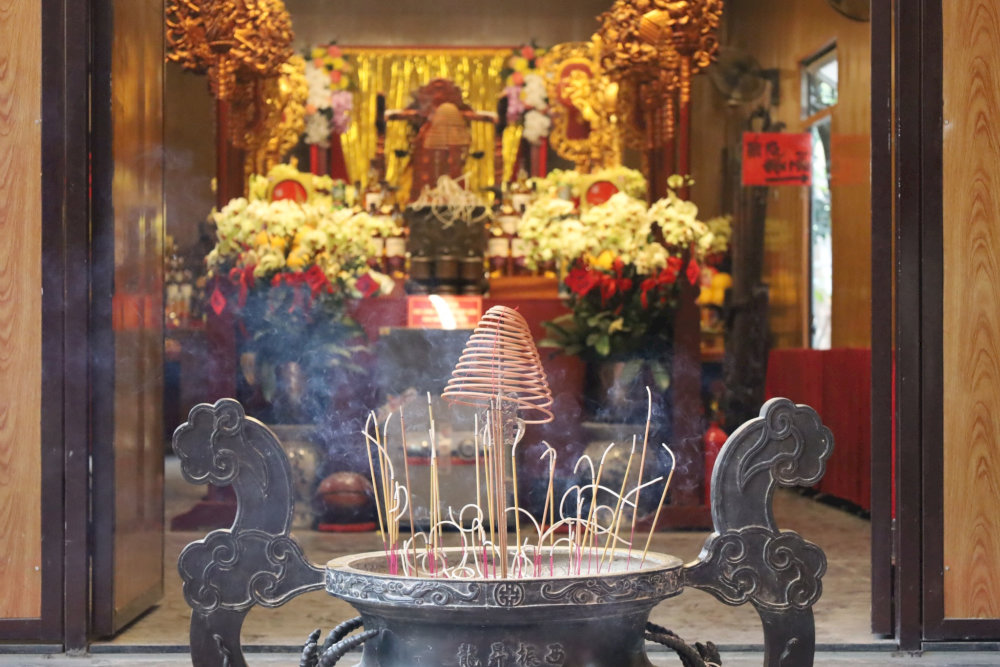 A grand incense burner (Lu huong) stands at the temple entrance, welcoming devotees